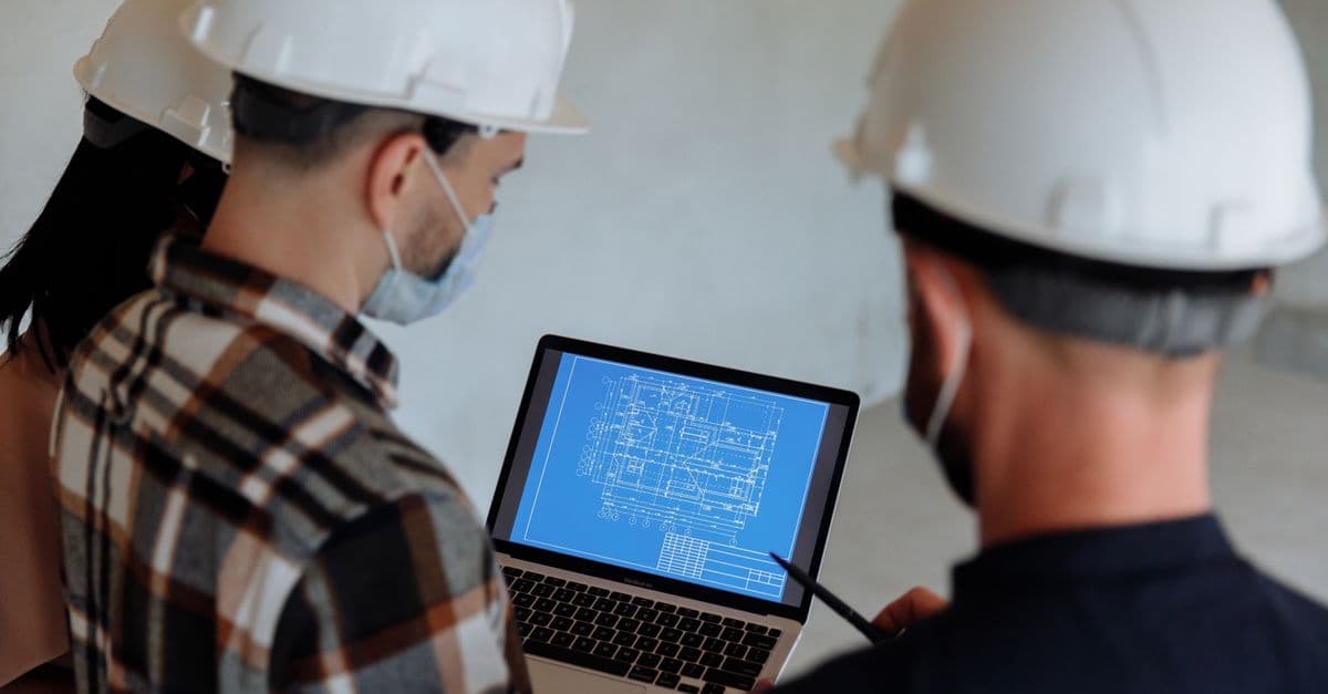 Engineers reviewing a blueprint on a laptop