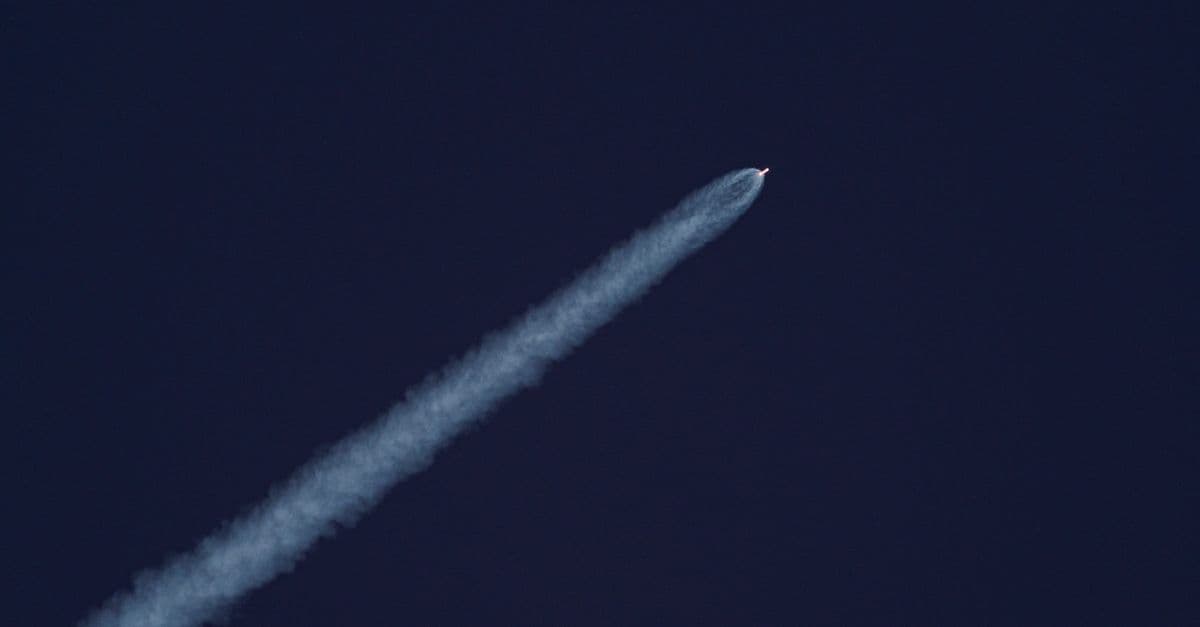 A rocket climbing into a clear sky